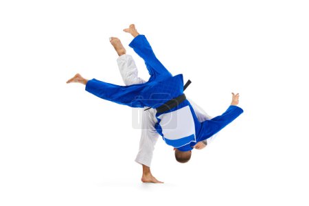 Photo for Two male professional sportsmen during match. Judo fighter attacking his opponent with leg technique isolated white background. Concept of martial art, combat sport, health, energy, fit. Copy space - Royalty Free Image