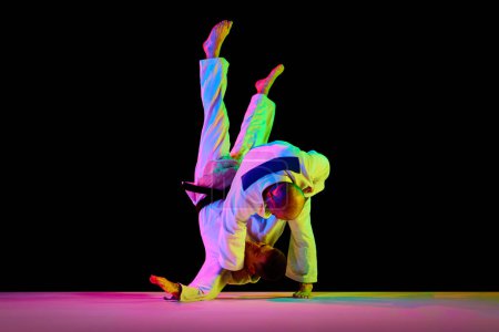 Téléchargez les photos : Portrait de sportifs, combattants des arts martiaux en kimono blanc combattant techniques d'exécution dans des mouvements isolés fond noir. Concept d'art martial, sport de combat, santé, énergie, forme physique. Espace de copie - en image libre de droit