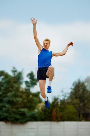 Photo for Leap of determination frozen in this captivating long jump photo. motivated young man, professional sportsman doing perfect jump. Concept of kinds of sport, championship, motivation, energy. - Royalty Free Image