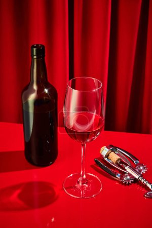 Photo for Freshly opened corkscrew bottle poured into classic tall glass of red wine served on red bar in luxury restaurant. Concept of night life, party time, holidays, Valentines Day, celebration. Ad - Royalty Free Image