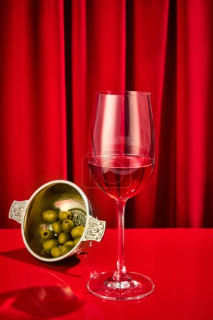 Photo for Close up photo of sweet red, pink seasoned wine served in high glass classy with olives in plate on bar counter at restaurant. Concept of night life, party time, holidays, Valentines Day, celebration. - Royalty Free Image