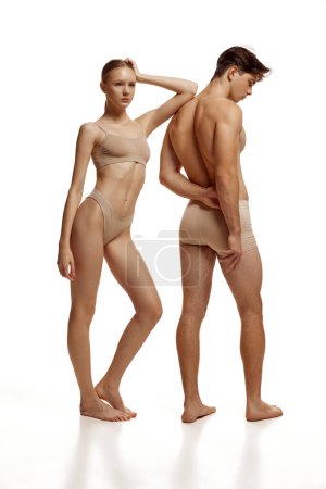 Foto de Retrato de cuerpo de pareja desnuda, mujer y hombre con cuerpos atléticos perfectos posando en ropa interior beige sobre fondo blanco estudio. Concepto de belleza, amor, cuidado corporal, productos cosméticos, moda - Imagen libre de derechos