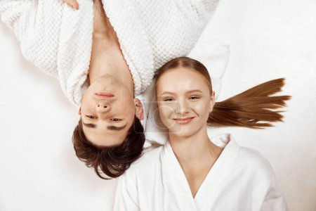 Photo for Visit to spa salon. Top view portrait of happy smiling young people, lovely couple lying against white studio background. Concept of beauty, spa resort, relationship, love, selfcare treatment. - Royalty Free Image
