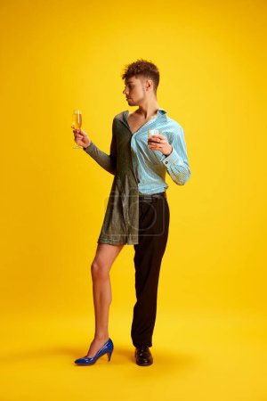 Photo for Toast to harmony of masculinity and femininity. Model, elegantly dressed in half-dress and smart casual costume, holds glasses of whiskey and sparkling wine. Concept of self-expression, fashion, style - Royalty Free Image