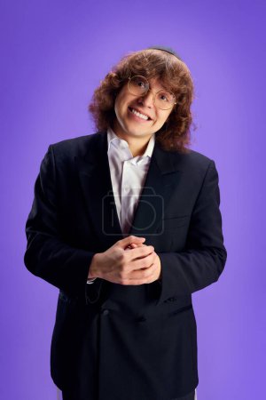 Photo for Smiling man with curly hair in round glasses dressed in formal suit looking at camera against purple background. Purim, business, festival, holiday, celebration Pesach or Passover, religion concept. - Royalty Free Image