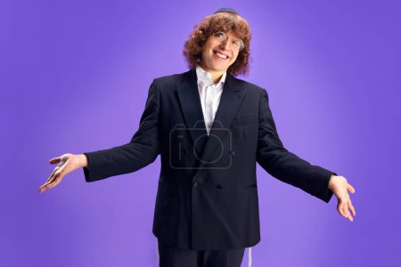 Photo for Portrait of young man in round glasses look friendly at camera and spread arms against vivid purple background. Purim, business, festival, holiday, celebration Pesach or Passover, Judaism concept. - Royalty Free Image