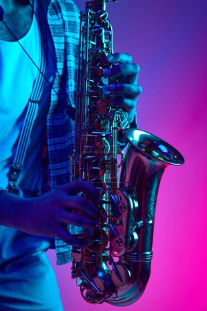 Téléchargez les photos : Photo rapprochée de musiciens jouant de la corde de jazz sur fond rose-bleu dans un néon mixte. Improvisation. Concept d'instrument de musique classique, concerts et festivals. Publicité - en image libre de droit