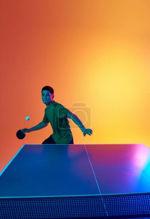 Photo for Young Asian man, table tennis athlete preparing for return, hit ball in neon light against warm yellow gradient background. Dynamic gel portrait. Concept of professional sport, healthy lifestyle. Ad - Royalty Free Image