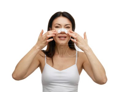 Retrato de mujer con parche blanco para limpiar la nariz de puntos negros sobre fondo blanco del estudio. Concepto de cuidado facial y belleza, tratamientos de spa, productos de cosmetología, dermatología.