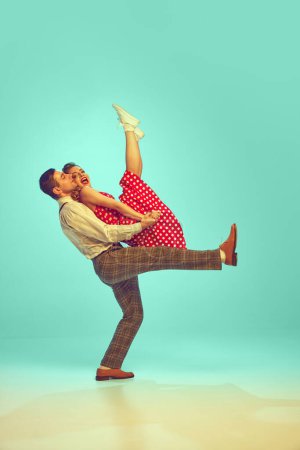 Male and female dancers in playful dance step against gradient mint background. Retro vibes. Dance rhythms. Concept of comparisons of eras, music, energy, happiness, mood, action, fashion and style.