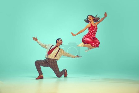 Swing dancers radiating happiness while performing energetic dance moves in motion against gradient mint background. Concept of music, hobby, art, energy, happiness, mood, action, 60s, 70s culture
