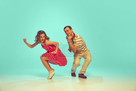 man and woman, talented dancers in retro style clothes dancing swing, boogie-woogie against gradient mint background. Actors in motion. Concept of music, energy, happiness, mood, action