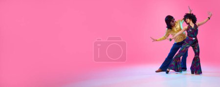 Banner. Vibrant couple in 70s wear, woman with afro hairstyle and man with sunglasses against gradient pink studio background. Concept of American culture, 1970s, 1980s fashion, comparisons of eras.