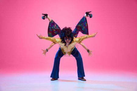 Retro dance styles. Attractive young couple, man and woman performing disco against gradient pink studio background. Concept of American culture, 1970s, 1980s fashion, music, comparisons of eras.