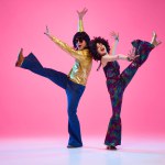 Full length portrait of talented people, dancers duo energetically moves against gradient pink studio background. Concept of American culture, 1970s, 1980s fashion, music, art, comparisons of eras.