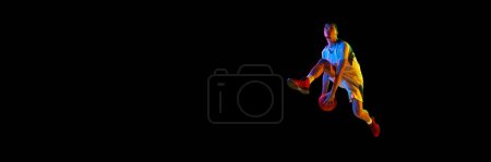 Banner. Junge Basketballspielerin in Bewegung in Neonlicht vor schwarzem Hintergrund mit negativem Raum, um Ihren Text einzufügen. Konzept von Sport, Energie, Kraft und Stärke, Spiel, Meisterschaft, Turnier.