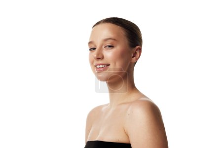 Portrait of young beautiful woman with bare shoulders looking at camera against white studio background. Concept of natural beauty people, injections, wellness, spa procedures, cosmetology. Ad
