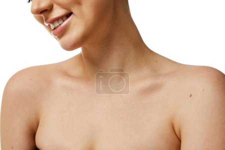 Cropped photo of young female neckline with smooth, healthy skin against white studio background. Model smiling. Concept of natural beauty people, injections, wellness, spa procedures, cosmetology. Ad