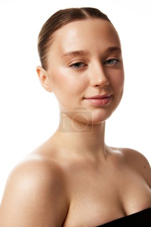 Portrait of young beautiful woman with bare shoulders looking at camera against white studio background. Concept of natural beauty people, injections, wellness, spa procedures, cosmetology. Ad