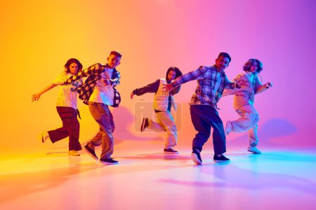 Talentierte junge Tänzer führen Streetstyle-Dance in Bewegung im Neonlicht vor farbenfrohem Studiohintergrund auf. Konzept aus Hobby, Sport, Mode, Action, Jugendkultur, Musik und Tanz.