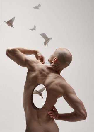 Contemporary art collage. Bald man in profile, muscles tense, with circular cutout in his back where paper crane appears inside. Concept of transformation and growth, piece and freedom, self love. Ad