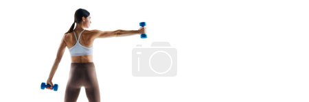 Banner. Young athletic woman training with dumbbells in motion against white studio background with negative space yo insert text. Concept of sport and recreation, movement, self care, action, energy.