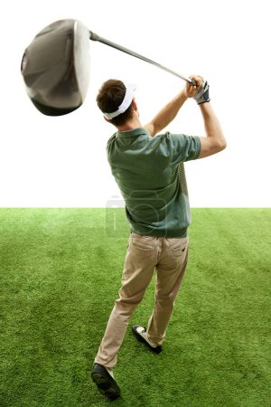 Rear view of man completing golf swing n mid follow-through with focus on club against white studio background. Concept of professional sport, luxury games, active lifestyle, action. Ad