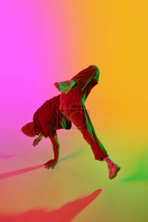 Dynamisches Foto einer zeitgenössischen Tänzerin in Bewegung im Neonlicht vor rosa-gelbem Hintergrund. Konzept von Hobby, Sport, Kreativität, Mode und Stil, Bewegung, Aktion. Anzeige