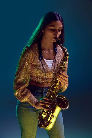 Photo for Portrait of young attractive woman, saxophonist performing jazz melodies in neon light against gradient background. Concept of art, music, hobby, classical music and modern lifestyle. Ad - Royalty Free Image