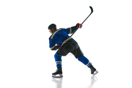 Photo for Ready to attack, skilled player, geared up and focused, glides with stick held high against white studio background. Concept of professional sport, competition, movement, energy, tournament, match. Ad - Royalty Free Image