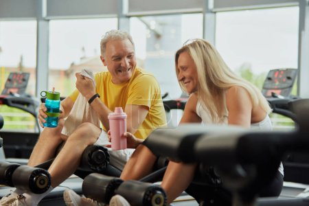 Photo for Two seniors in wearing sport gear share fun moment during exercising in modern fitness center. Concept of sport, active seniors in modern life, healthy lifestyle, fitness, strength and vitality. Ad - Royalty Free Image
