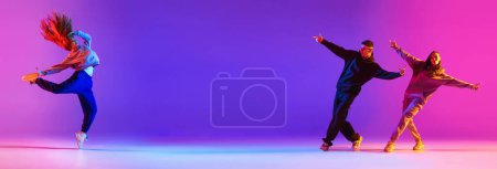 Photo for Banner. Young active couple, boys and girls dancing contemp, hip hop against gradient studio background in neon. Concept of contemporary dance style, youth, hobby, action and motion. Ad - Royalty Free Image