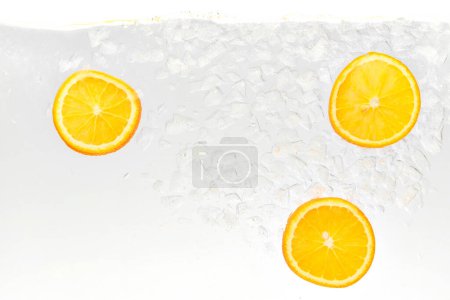 Textured photo of refreshing drink with sweet and sour citrus drink, orange, floating in glass of water. Abstract wallpaper. Concept of food and drinks, summer,vitamins, nutrition.