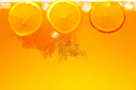 Textured photo. Orange slices with ice cubes adorns refreshing tropical drink. Abstract wallpaper. Sweet and sour. Concept of food and drinks, summer,vitamins, nutrition.