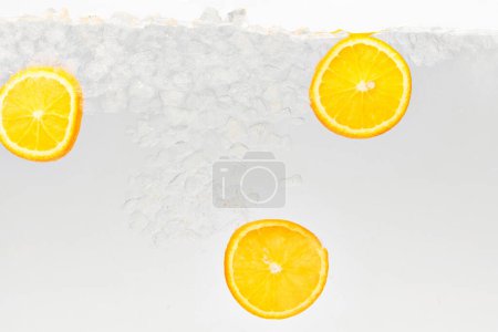 Close up photo of lemonade drink with slices of citrus fruit floating in liquid against white background. Textured photo. Abstract wallpaper. Concept of food and drinks, summer,vitamins, nutrition.