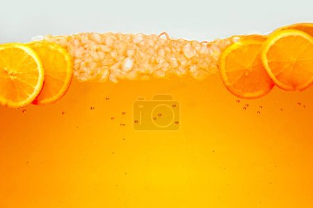 Close up photo of exotic drink with ice cubes and slices of sweet and sour citrus fruit, orange. Textured photo. Abstract wallpaper. Concept of food and drinks, summer,vitamins, nutrition.