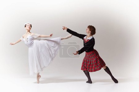 Anmutiges Ballettpaar. Ballerina balanciert in einem weißen Kleid mit floralem Haarschmuck zart auf Spitze und ihr Partner greift nach ihr. Kunstbegriff, Verschmelzung von Klassik und Moderne, Anmut.