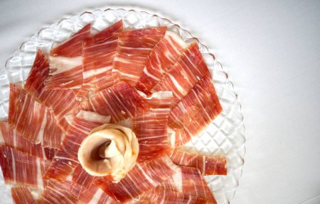 Iberian ham displayed on a plate, beautifully arranged with a flower pattern.