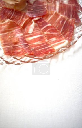 Sliced Iberian ham, delicately placed on a crystal plate.