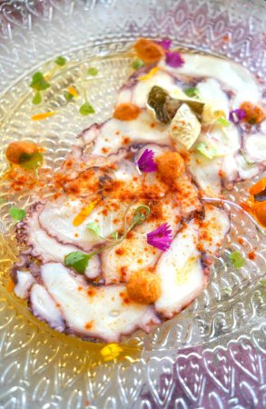 Tender octopus slices garnished with herbs and edible flowers.