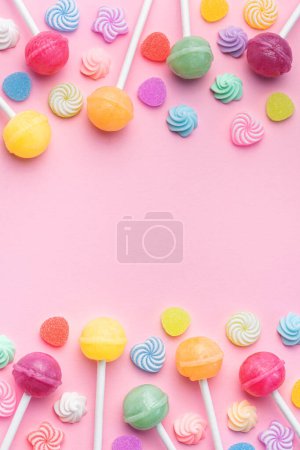 Foto de Coloridas piruletas dulces y caramelos sobre fondo rosa. Piso tendido, vista superior - Imagen libre de derechos
