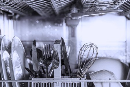 Vue de face de l'acier inoxydable automatique ouvert intégré entièrement intégré haut de gamme de lave-vaisselle avec ustensiles propres, couverts, verres, vaisselle, plaques à l'intérieur dans la cuisine moderne de la maison