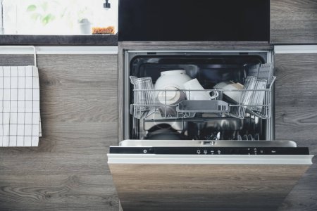 Photo for Closeup of opened automatic stainless built-in dishwasher machine inside modern home kitchen with clean utensil. Doing household chores, daily home routine, housework. Interior with kitchen appliances - Royalty Free Image
