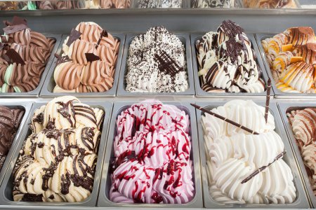 Display window in a store or ice cream parlour of assorted ice cream flavors for sale as summer takeaways displayed in metal trays