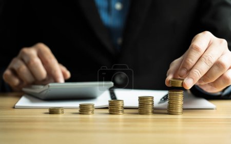 Finance bank and savings concept. Businessman hand putting coins and calculating. Saving Money. growth management, happy, income, tax, business, financial planning.