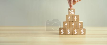 Photo for Interest rates and dividends, mortgage rates, investment returns, income, retirement Compensation fund, investment, dividend tax. Hand placed rising cube stick and upward direction percentage symbol. - Royalty Free Image