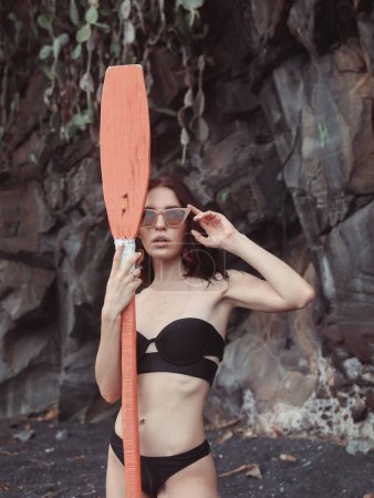 Photo for Girl on a beach. Lady on a Bali. Woman in a stylish swimsuit. Girl with red oar. - Royalty Free Image