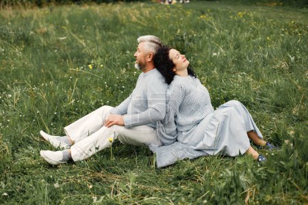 Photo for Close up romantic couple sitting in a autumn park. Man and woman wearing blue sweaters. Woman is brunette and man is gray. - Royalty Free Image