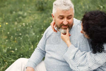 Photo for Close up romantic couple sitting in autumn park and hugging in daytime. Man and woman wearing blue sweaters. Focus on a womans face. - Royalty Free Image