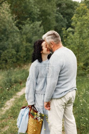 Photo for Close up romantic couple kissing in an autumn park. Man and woman wearing blue sweaters. Woman is brunette and man is gray. - Royalty Free Image